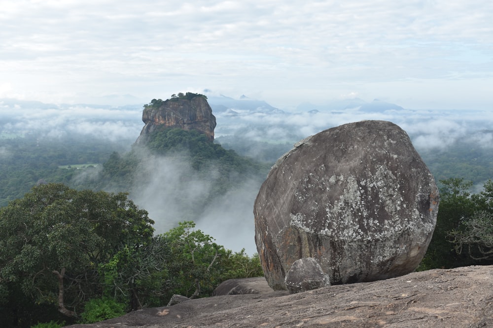 a large rock sitting on top of a lush green hillside