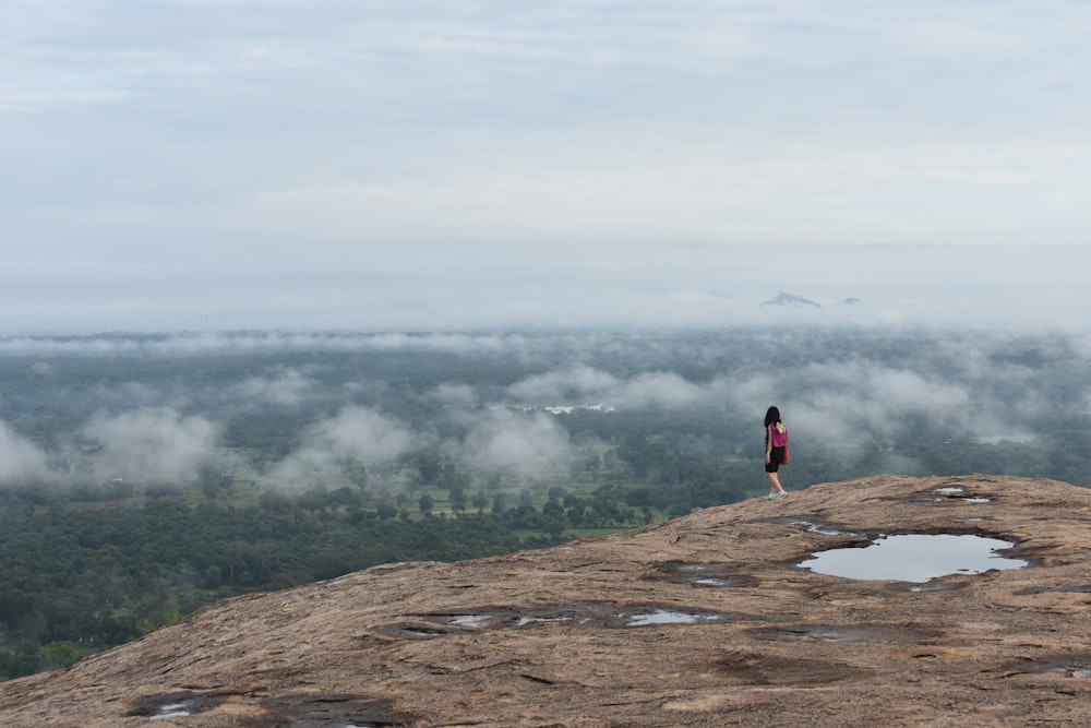 a woman standing on top of a large rock