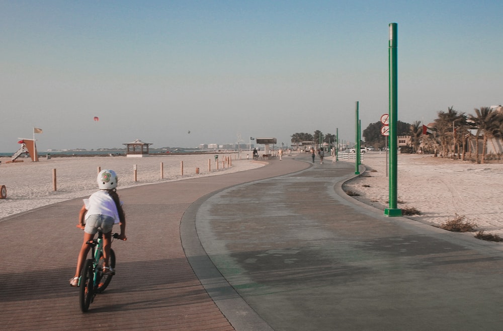 a person riding a bike on a boardwalk near the beach