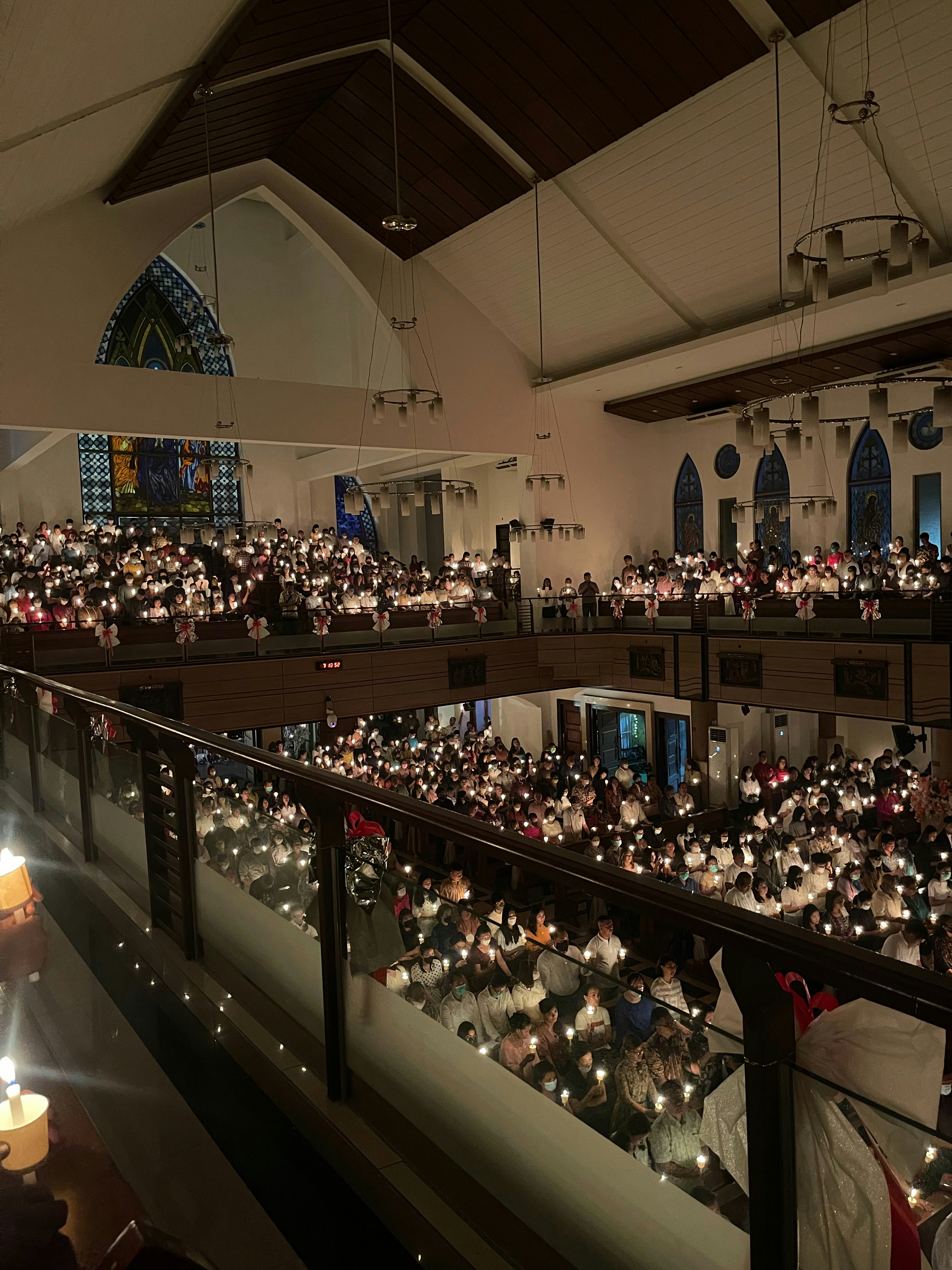 Congregation in warm candlelight, dark church interior, rows of people with heads bowed, reverent and peaceful atmosphere, dim warm lighting