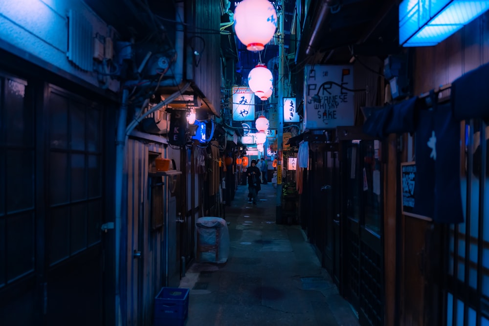 a narrow alley with lights hanging from the ceiling
