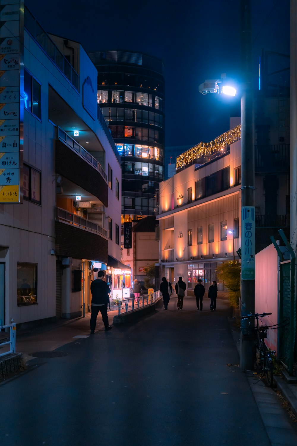 a group of people walking down a street at night