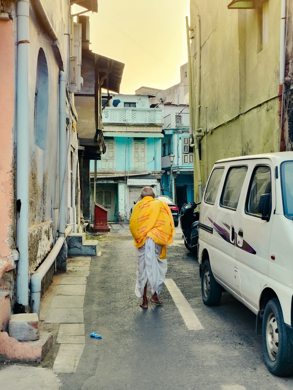 a man walking down a street holding a yellow umbrella