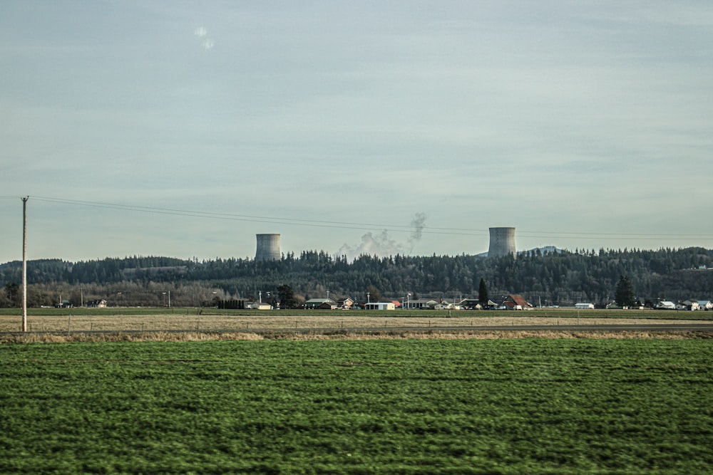 a green field with a power plant in the background
