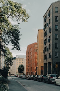 a city street lined with parked cars next to tall buildings
