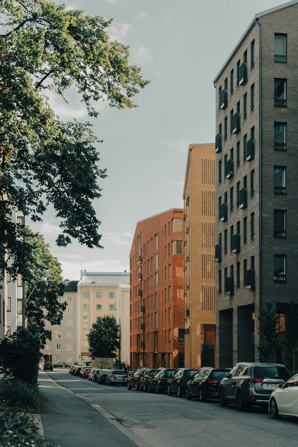 a city street lined with parked cars next to tall buildings