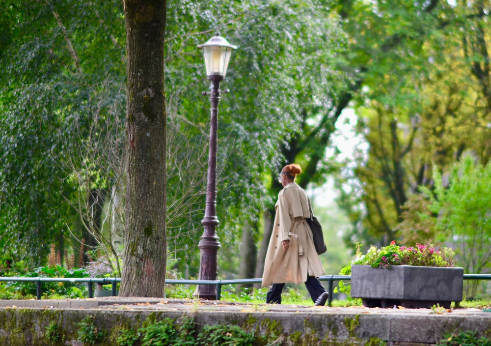 a woman walking down a sidewalk next to a lamp post