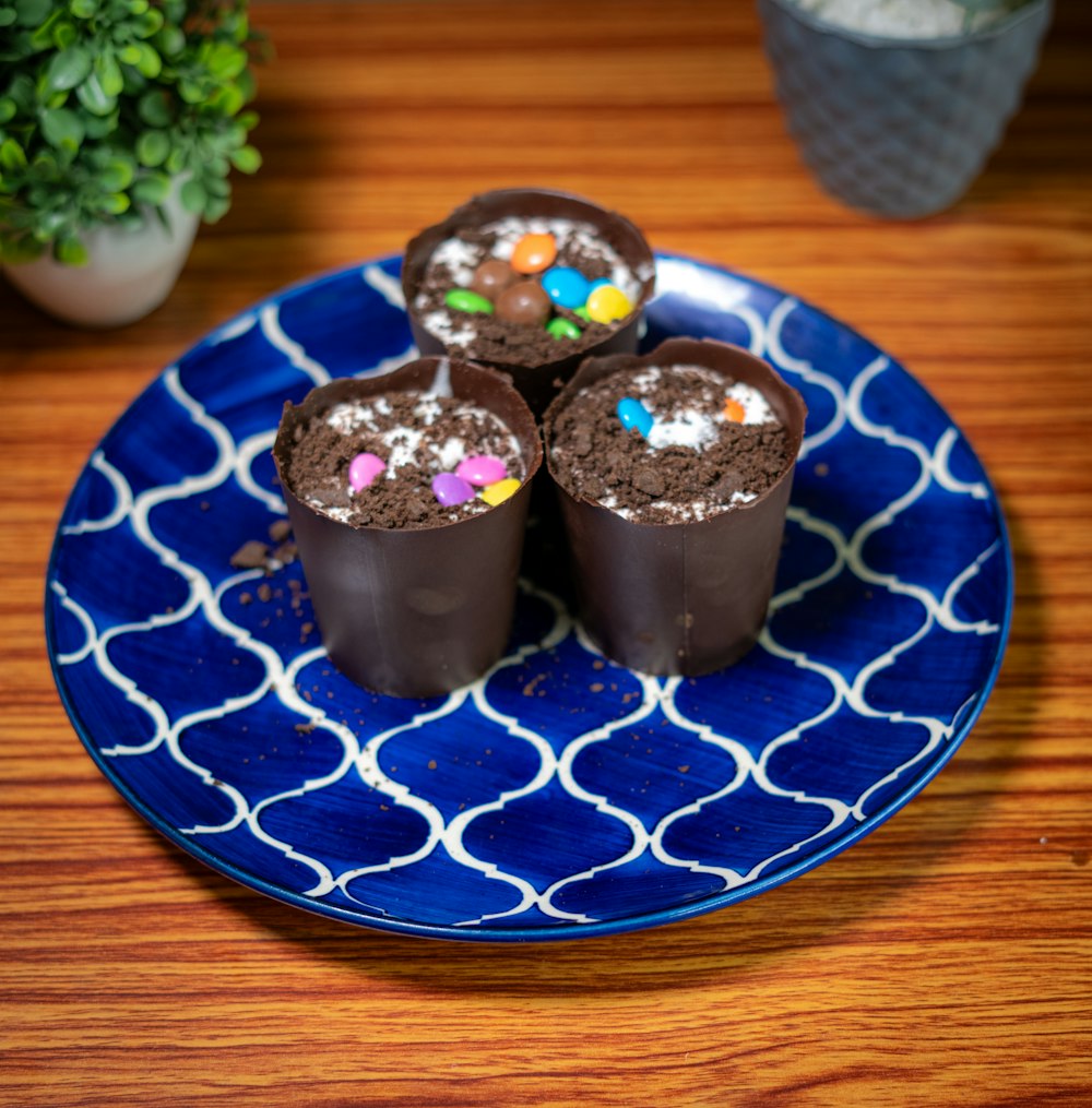 a blue plate topped with three chocolate cupcakes