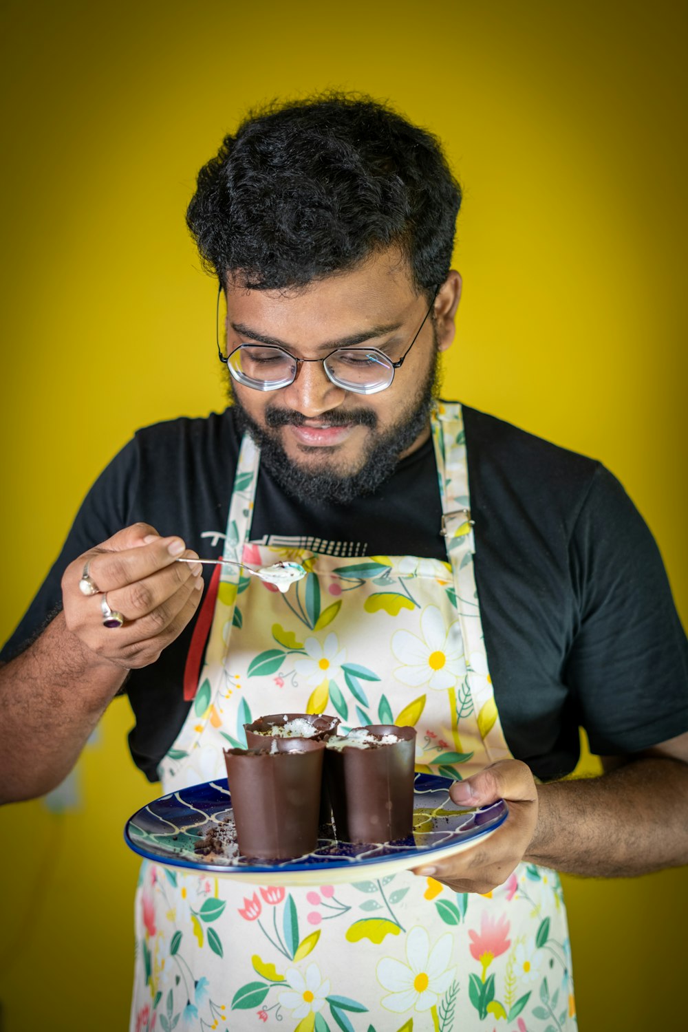 a man in an apron holding a tray of cups