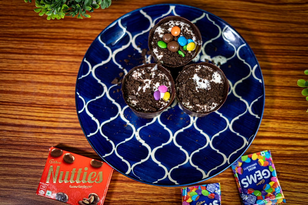 a blue plate topped with three chocolate cupcakes