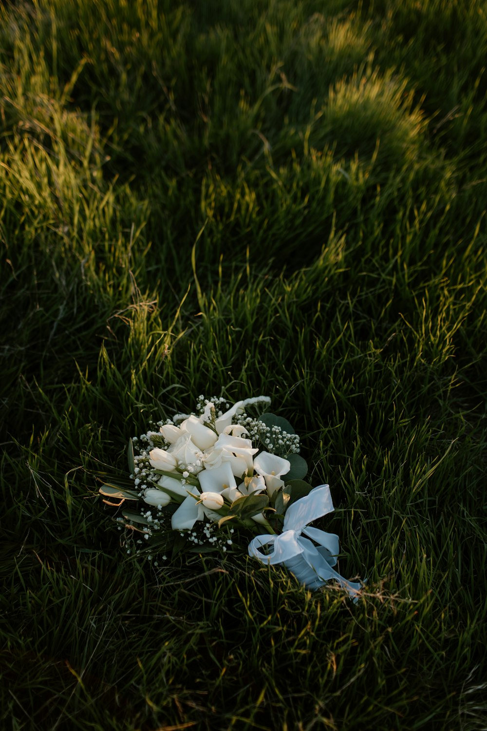 a bouquet of white flowers sitting on top of a lush green field