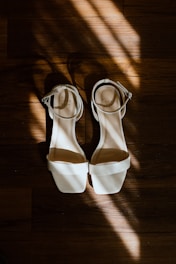 a pair of white shoes sitting on top of a wooden floor