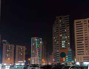 a parking lot filled with lots of cars next to tall buildings