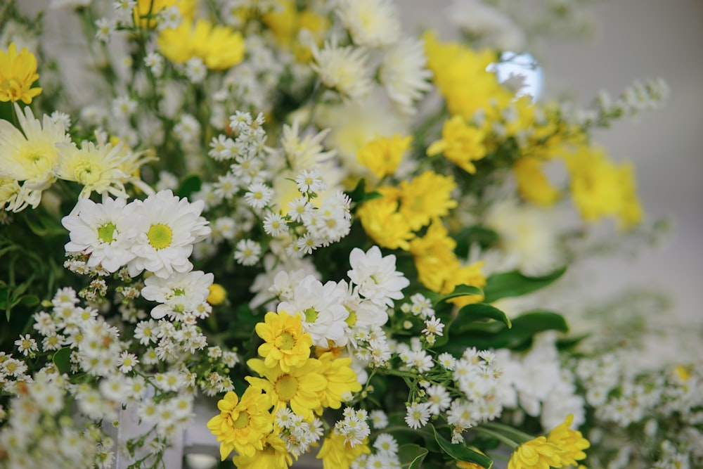 a bunch of yellow and white flowers in a vase