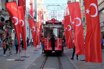 a trolley car on a street with flags on it