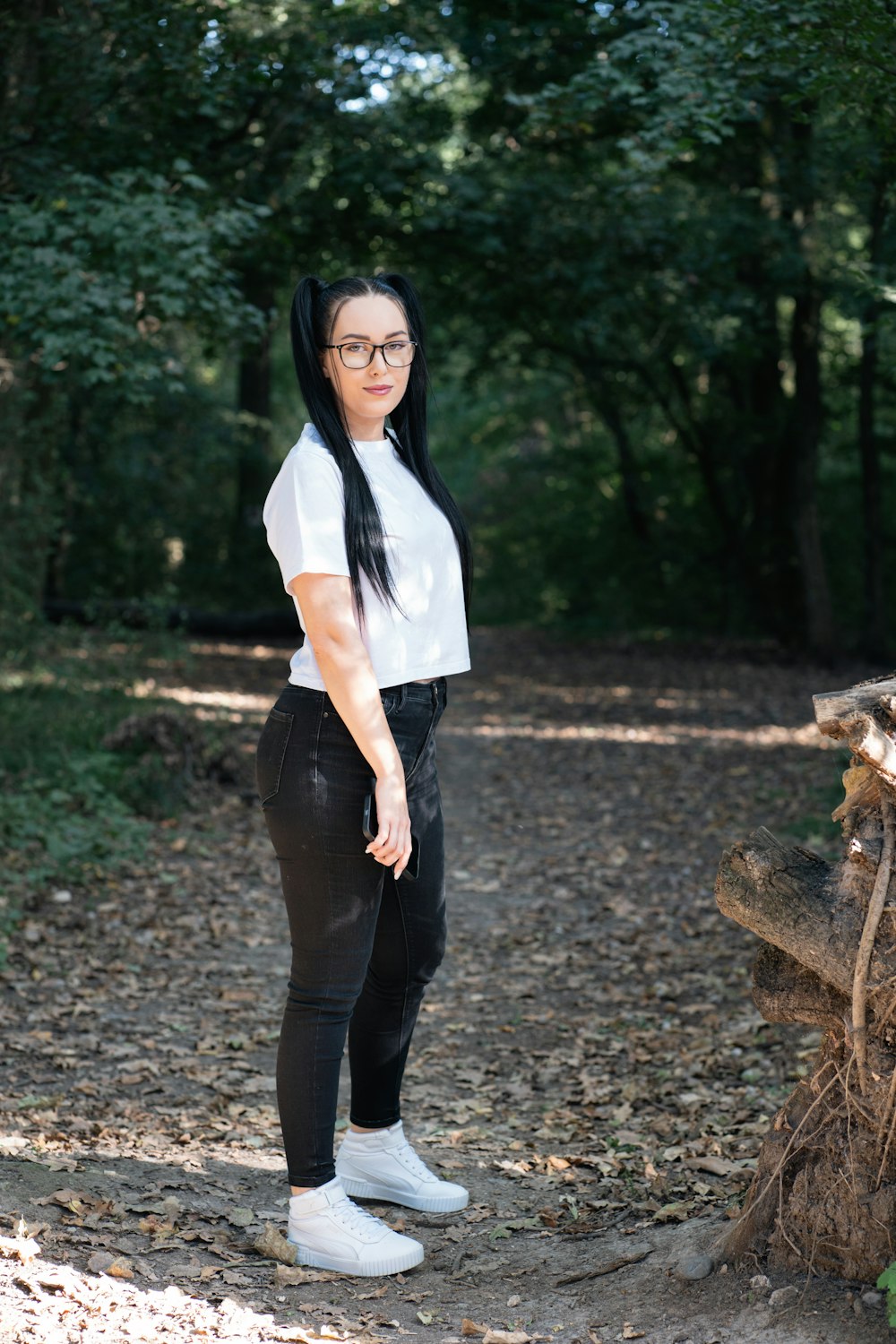 a woman with long black hair standing in the woods