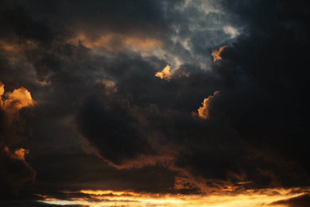 a dark sky with clouds and a plane in the foreground