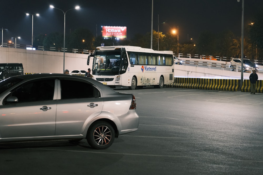 a silver car parked in a parking lot next to a bus