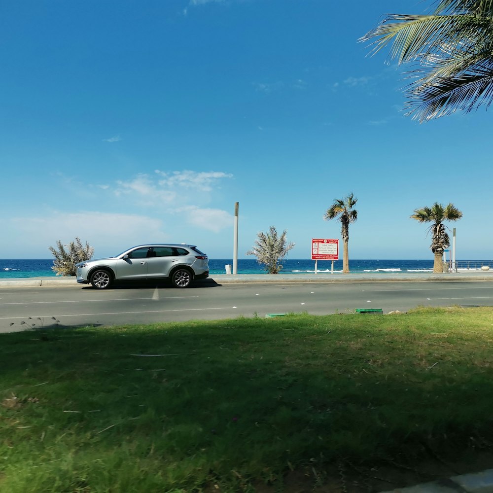 a car driving down a street next to the ocean