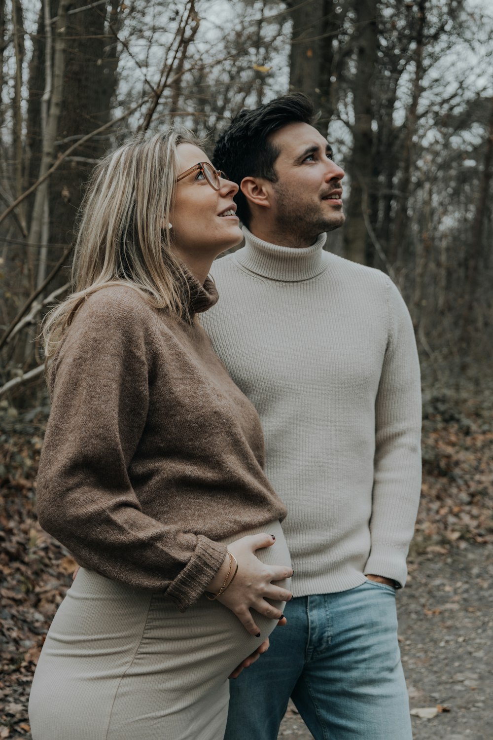 a man and a woman standing next to each other in the woods