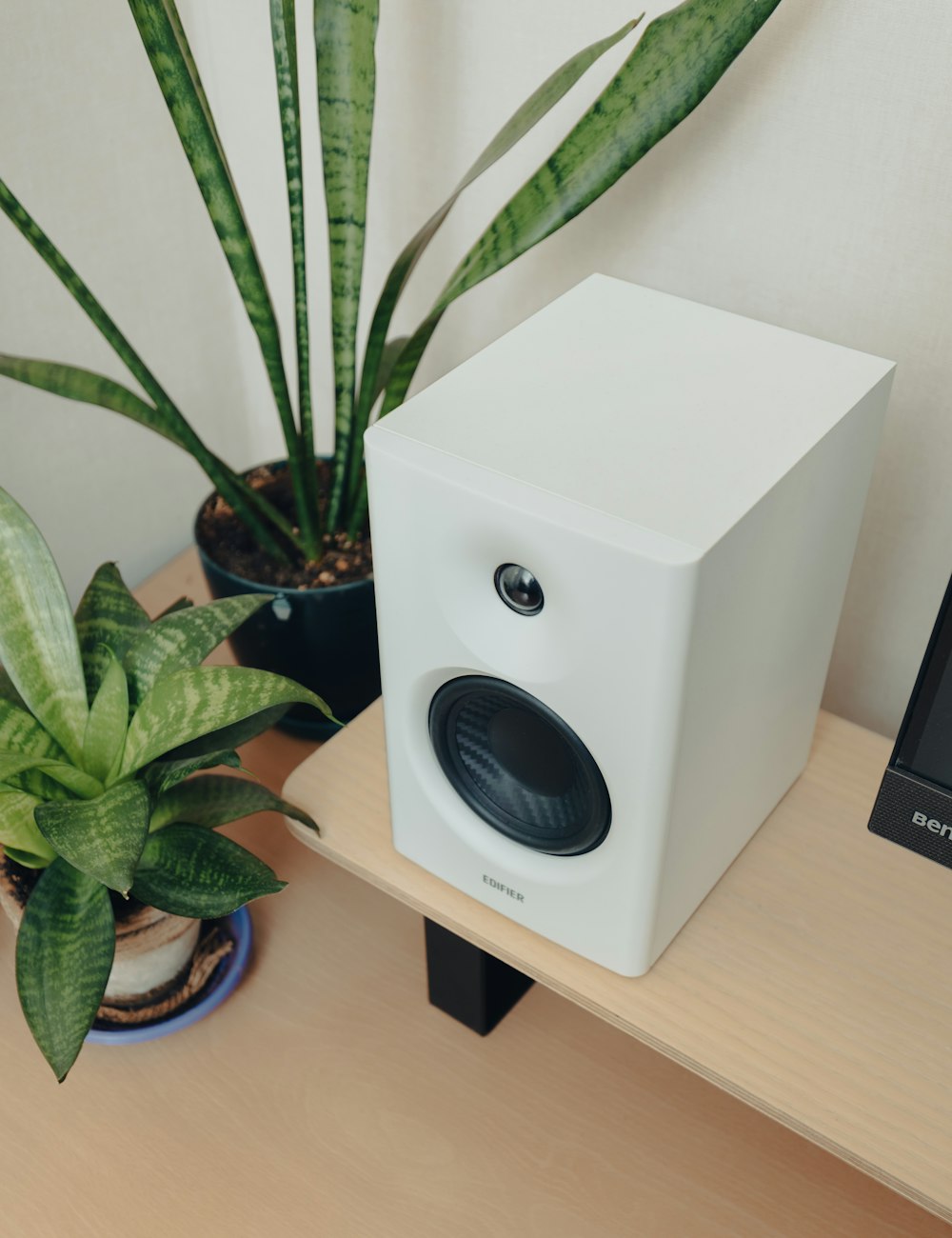 a white speaker sitting on top of a wooden table