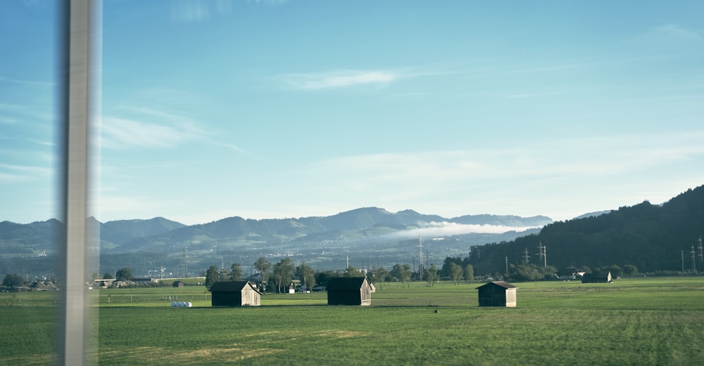 a grassy field with several buildings in the distance