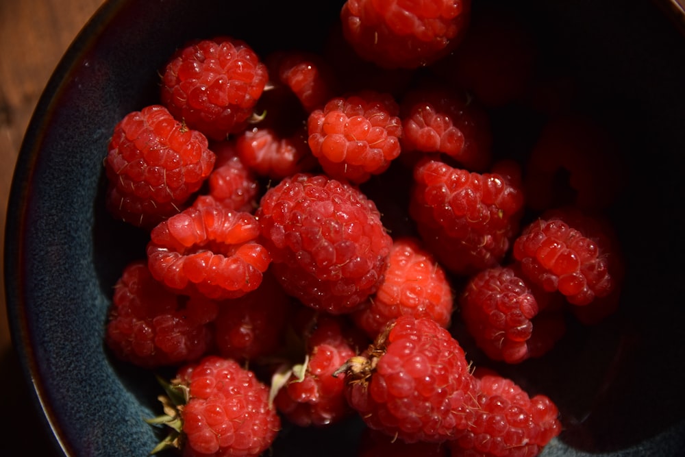 a bowl filled with raspberries on top of a wooden table