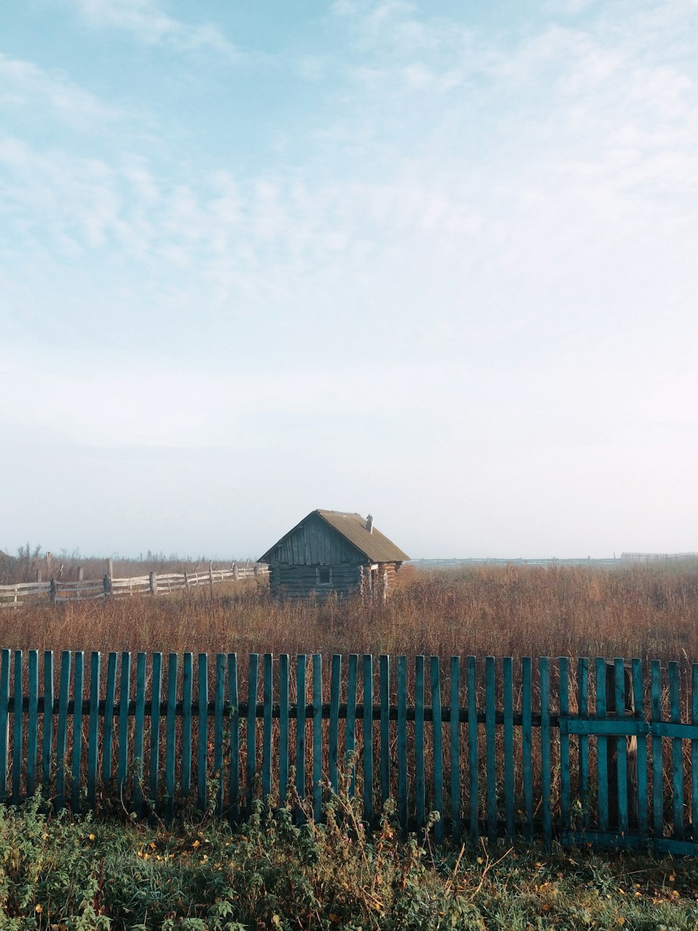 a wooden fence in a field with a barn in the background