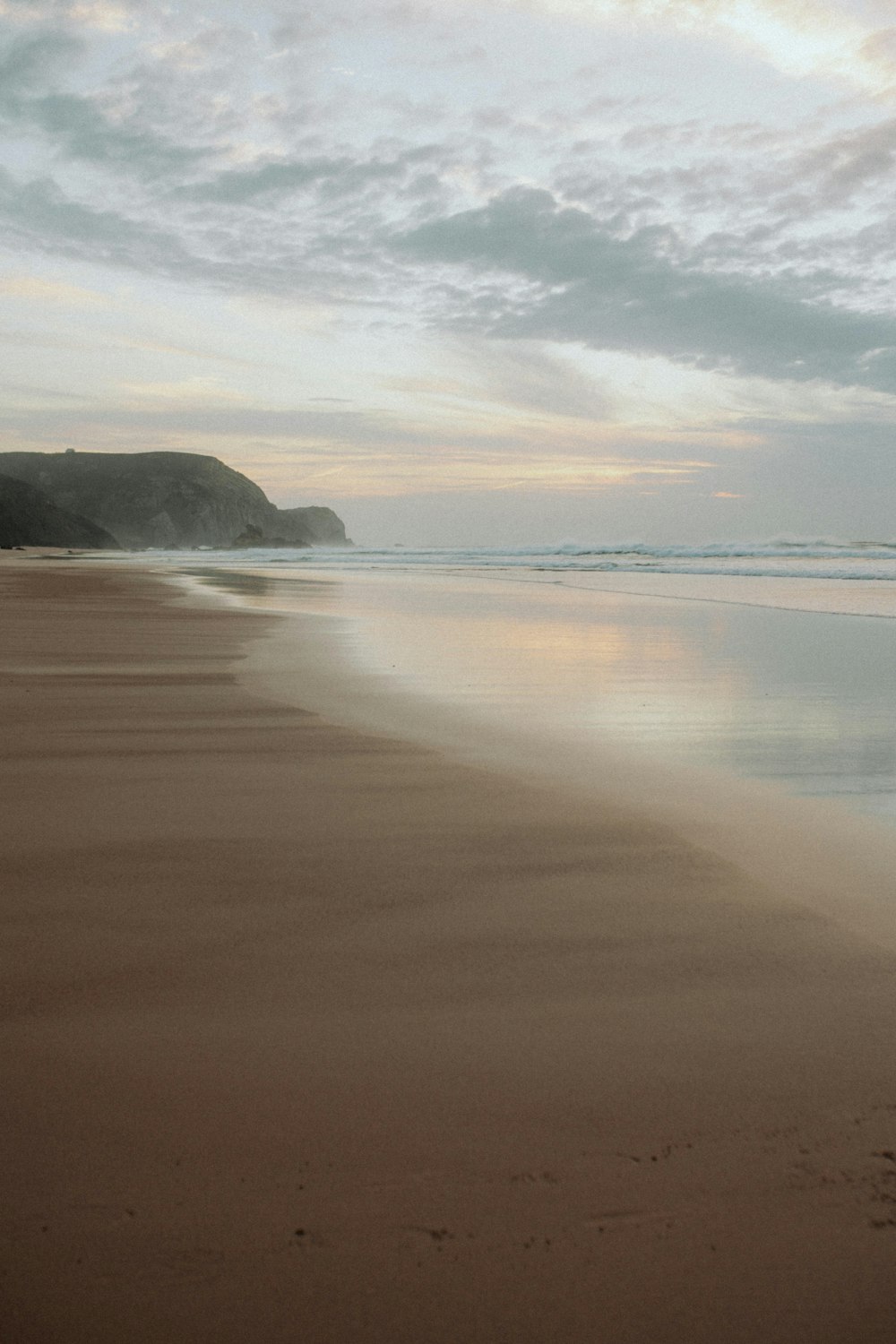 a person walking on a beach with a surfboard