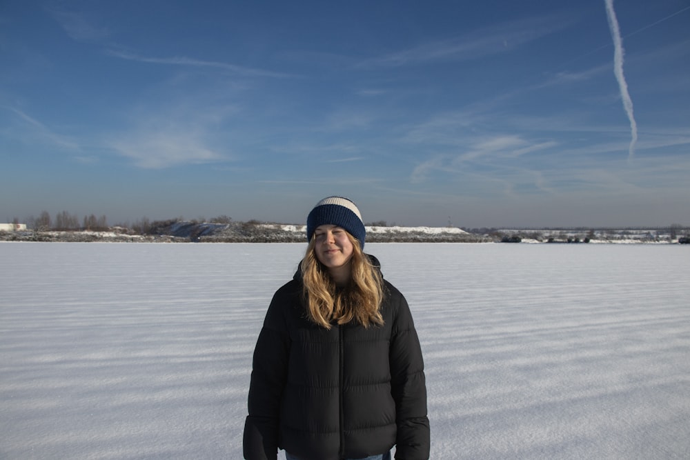 a woman standing in the middle of a snow covered field
