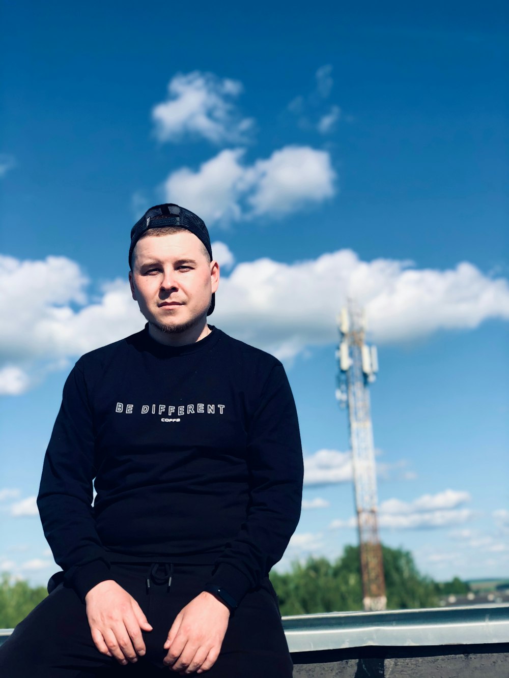 a man sitting on a bench in front of a blue sky