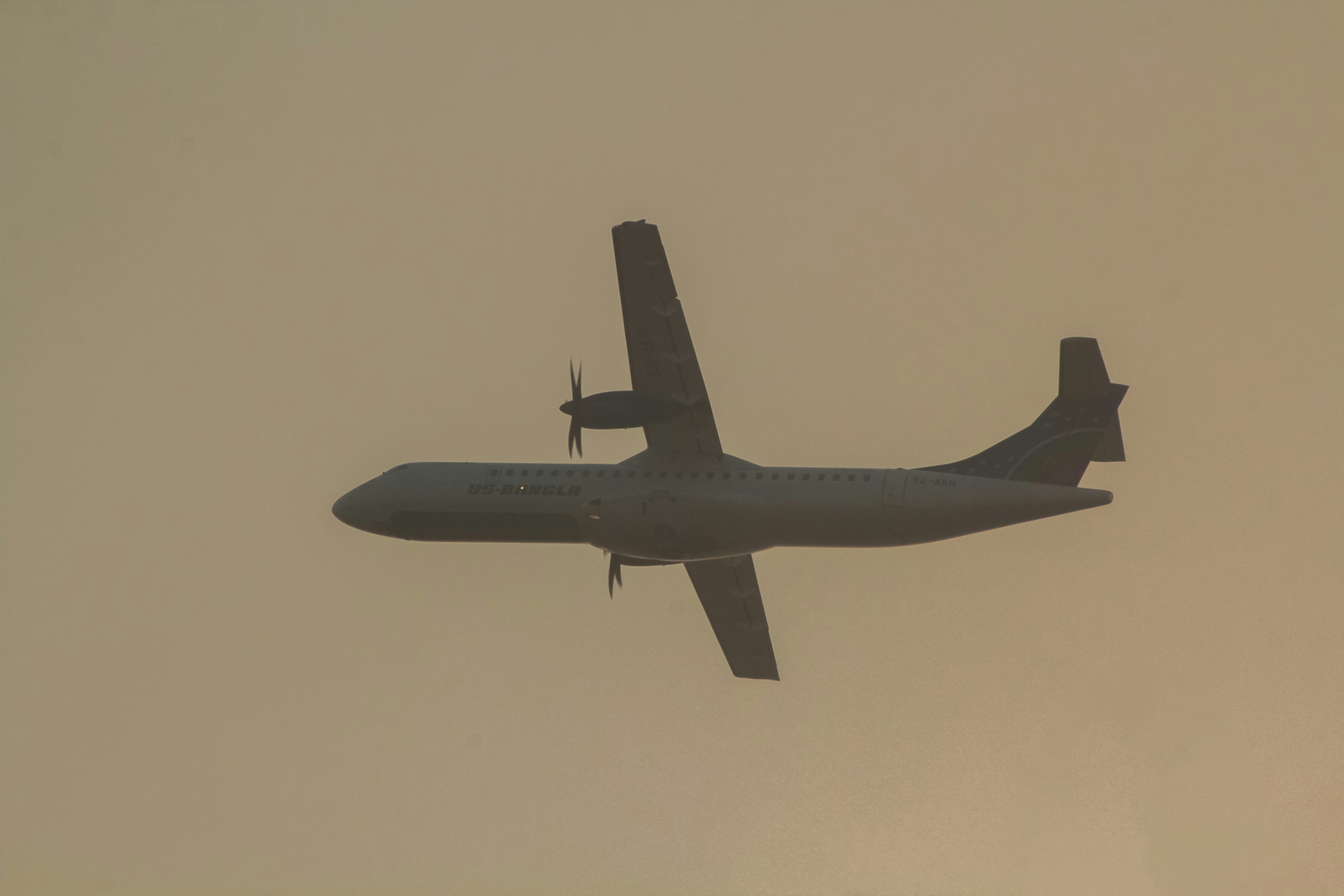 an airplane is flying in the sky on a hazy day, ATR72-600 of US-Bangla.
