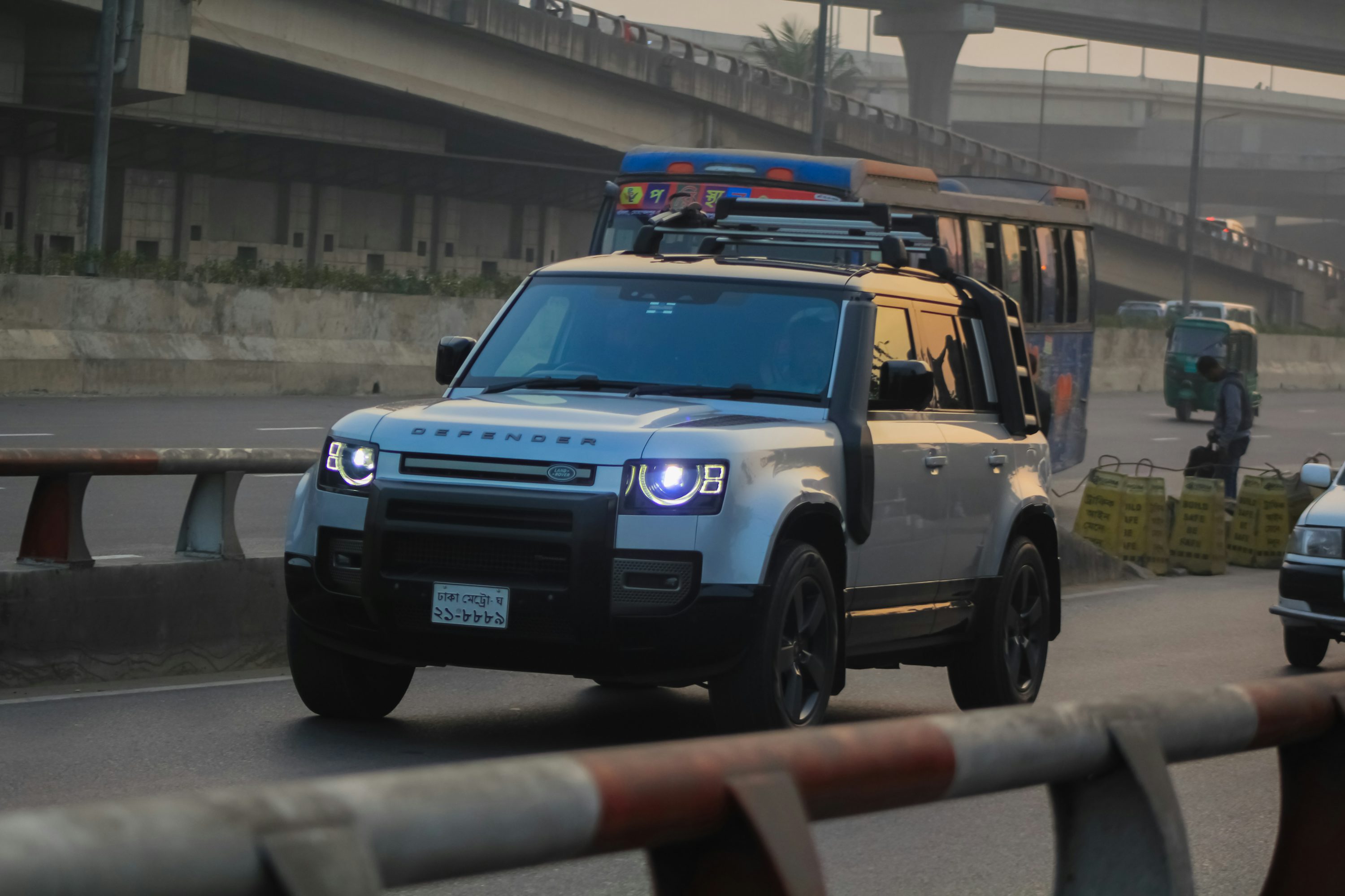 a silver land rover driving down a street next to a bridge