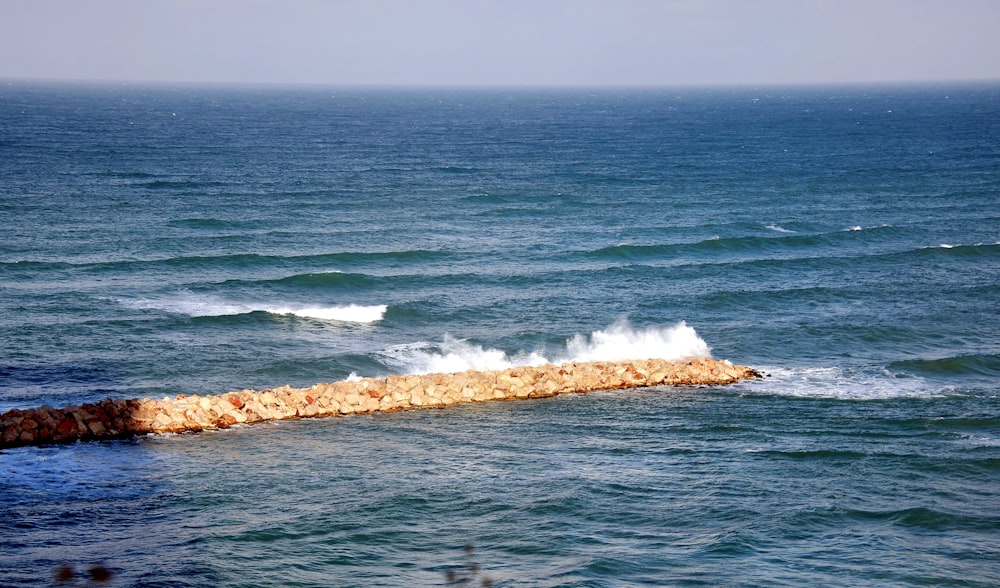 a rock wall in the middle of the ocean