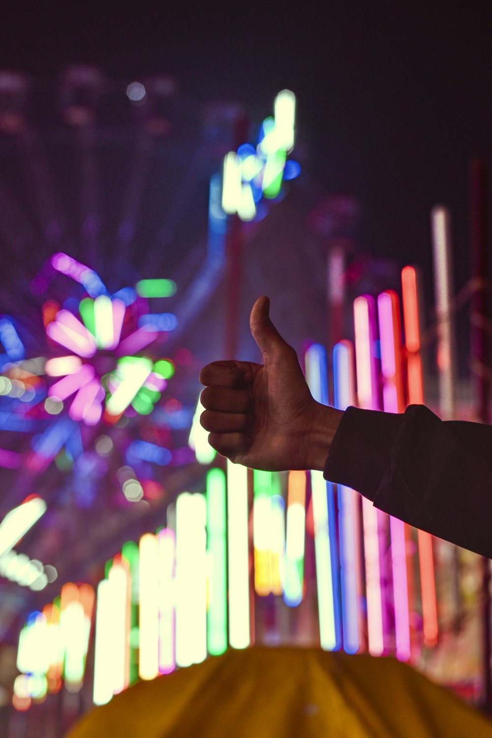 a person giving a thumbs up in front of a ferris wheel