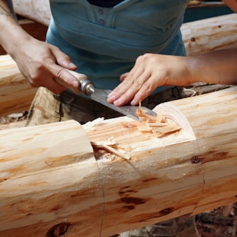 a person cutting a piece of wood with a knife