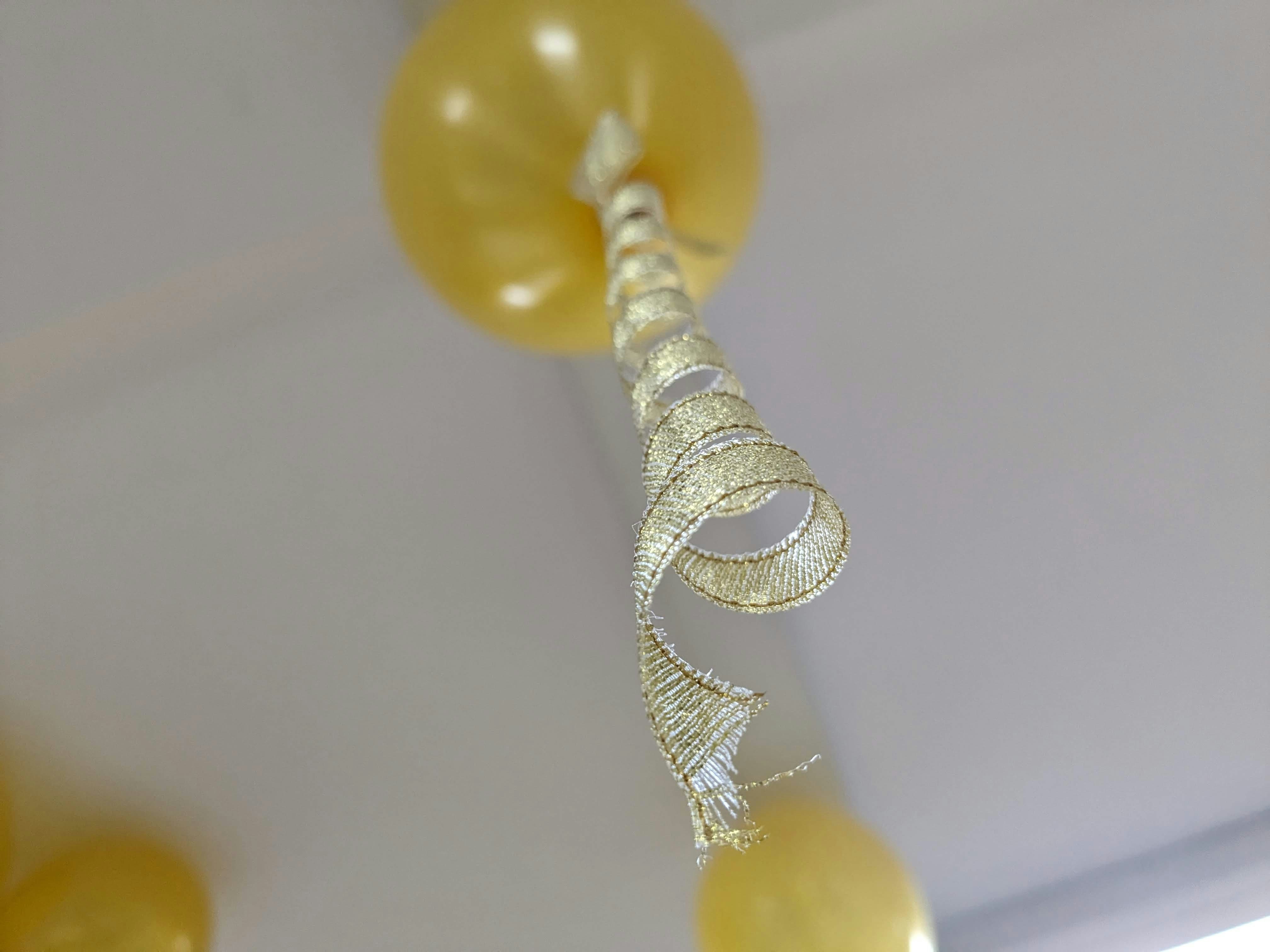 a bunch of yellow balloons hanging from a ceiling