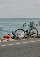 a bicycle parked on the side of a road next to the ocean