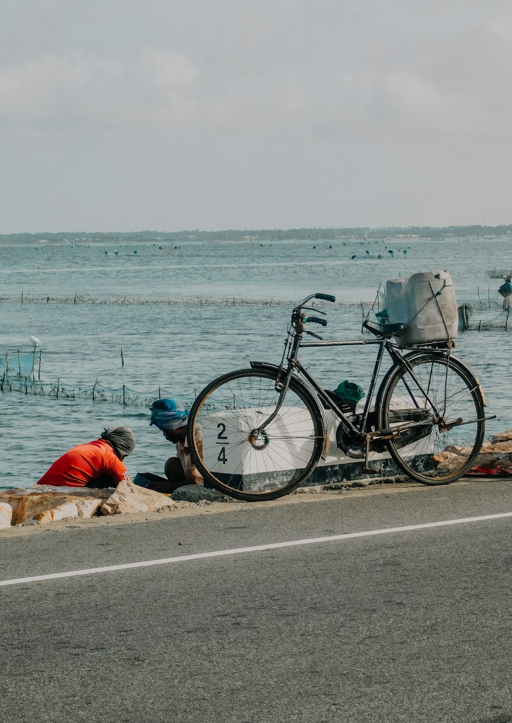 a bicycle parked on the side of a road next to the ocean