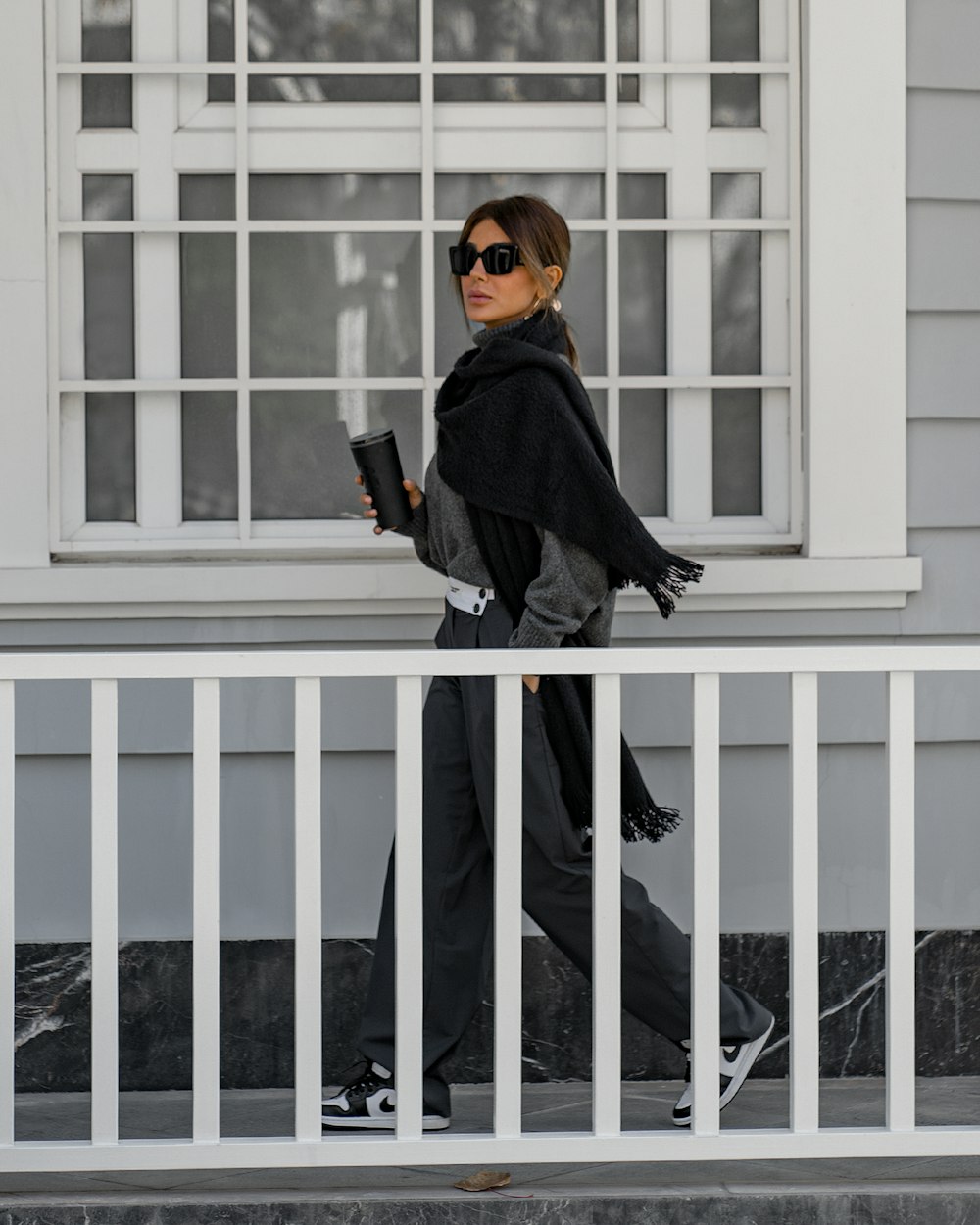 a woman walking down a street while holding a cup of coffee