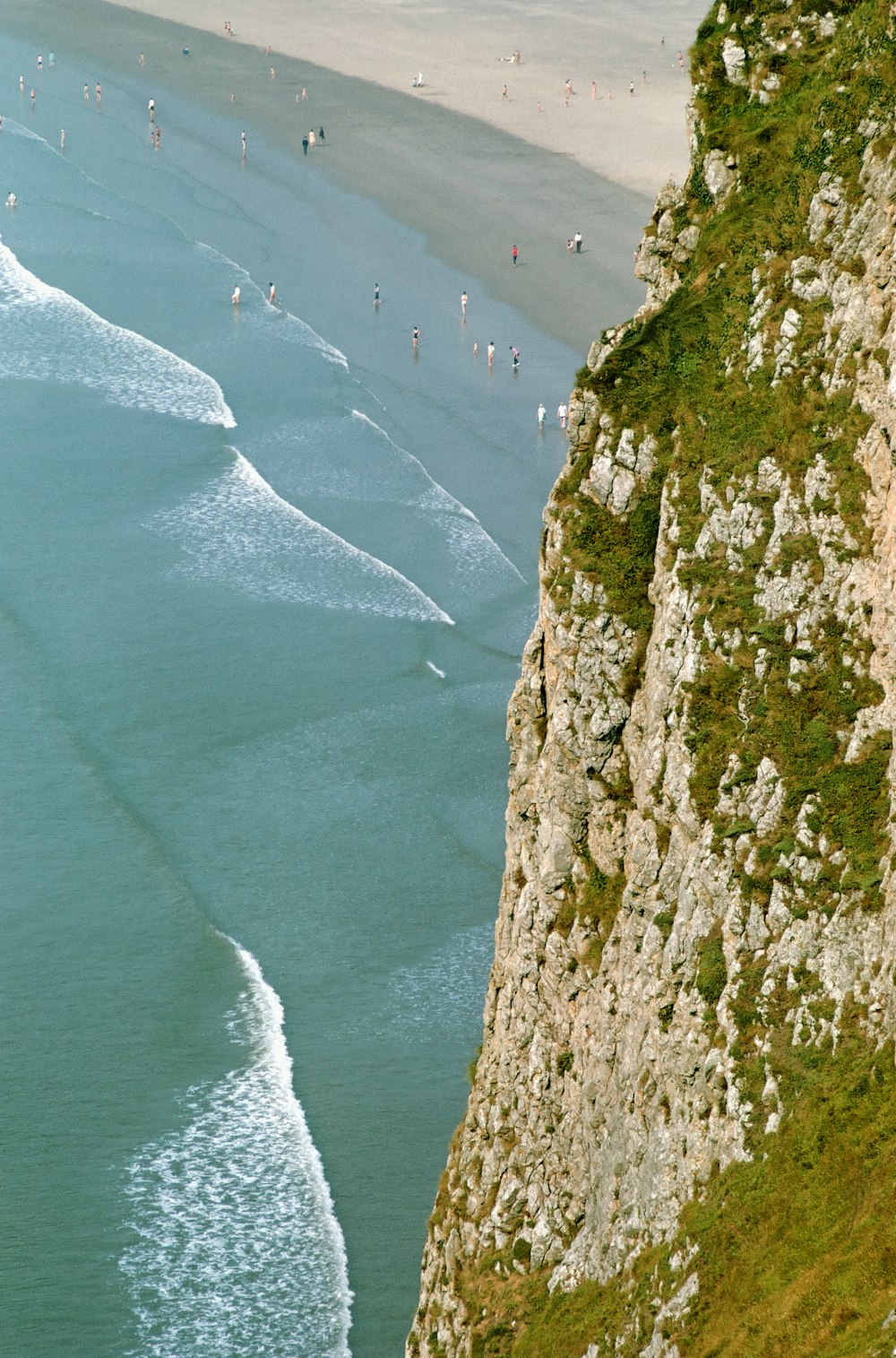 a group of people standing on top of a cliff next to the ocean