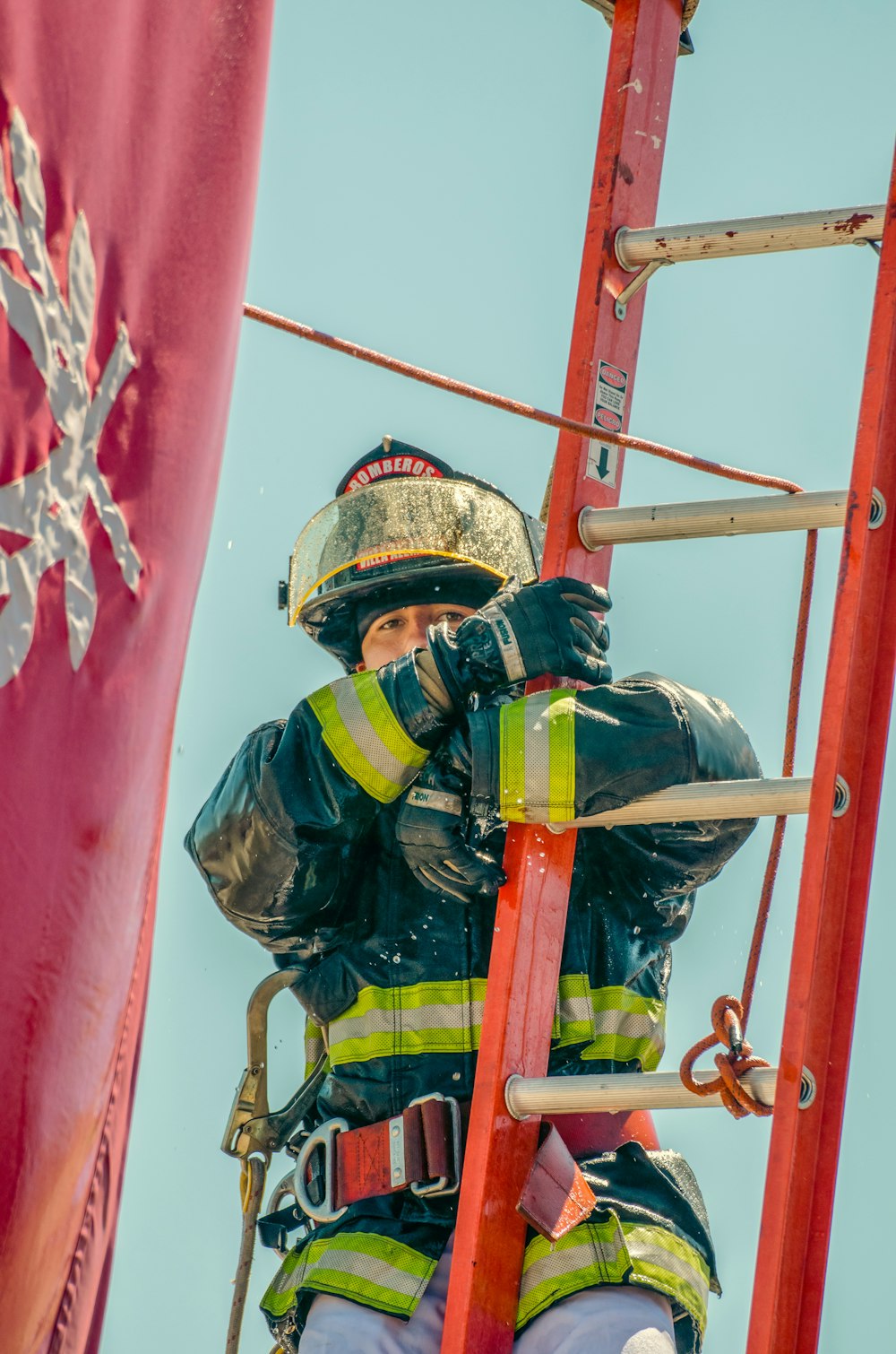 a fireman climbing up a ladder next to a flag