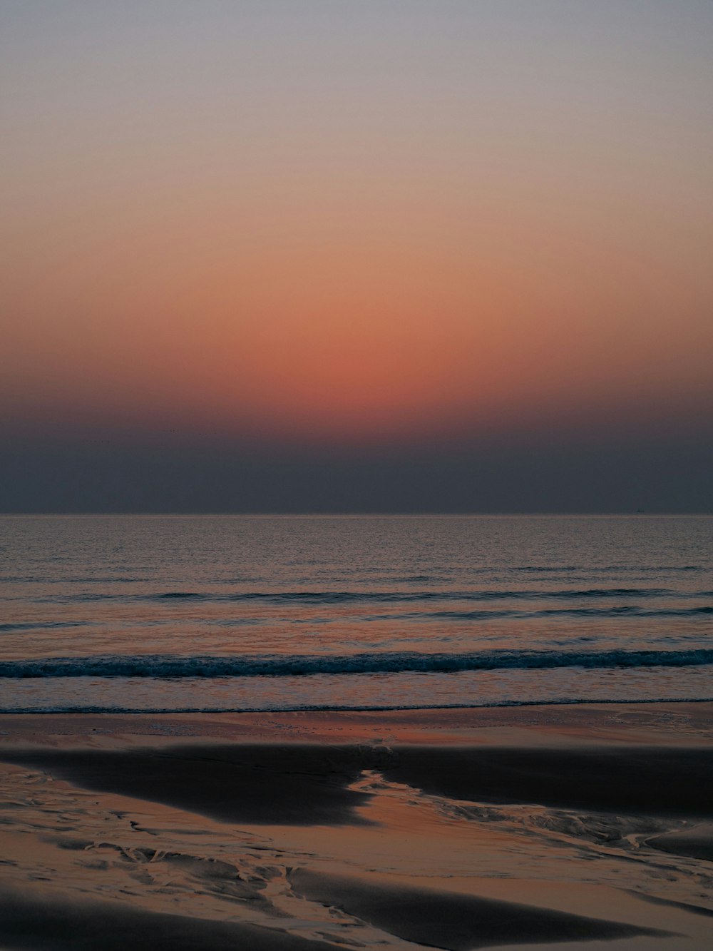 the sun is setting over the ocean on the beach