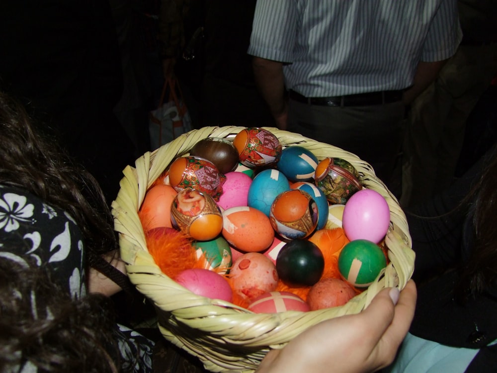 a person holding a basket full of painted eggs