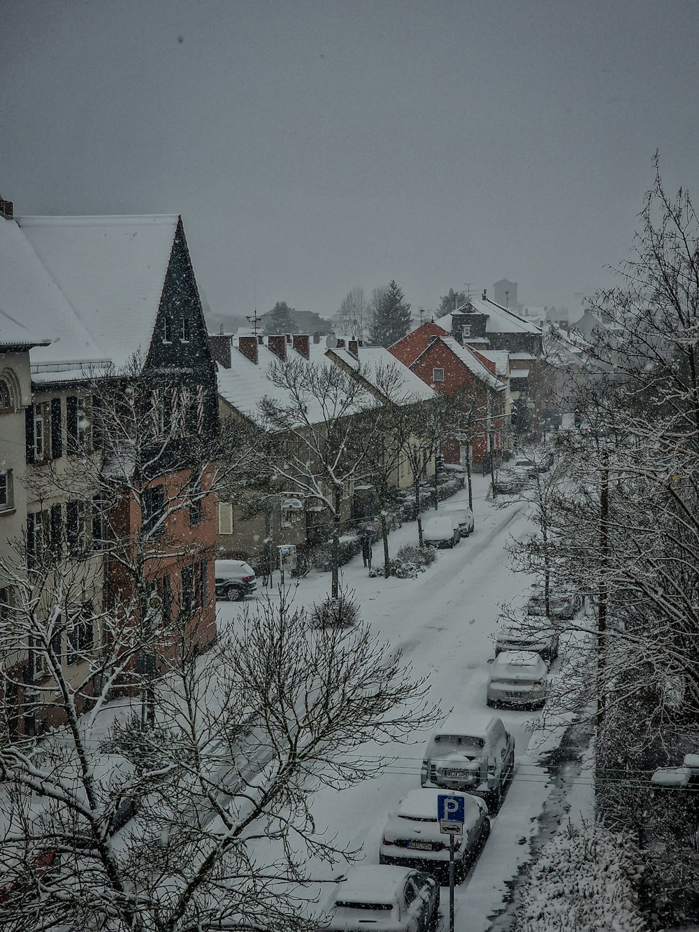 a snow covered street with cars parked on the side of it