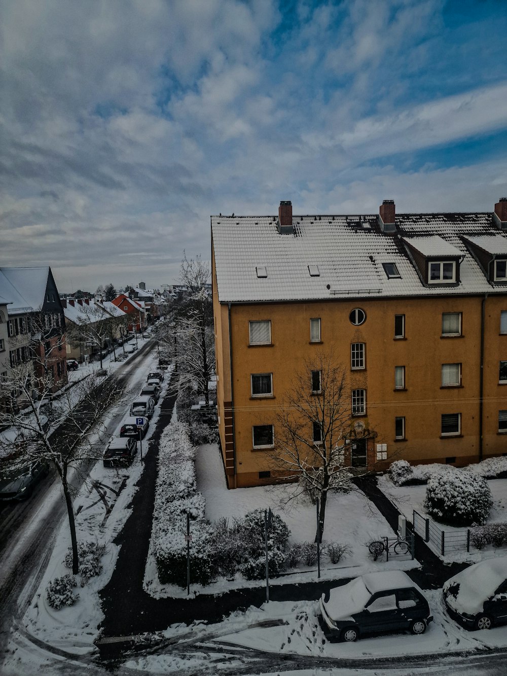 a snow covered street with cars parked on the side of it