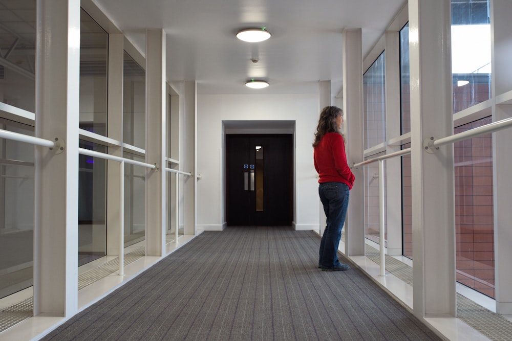 a woman in a red shirt is standing in a hallway