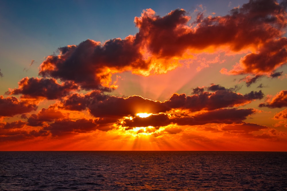 the sun is setting over the ocean on a cloudy day