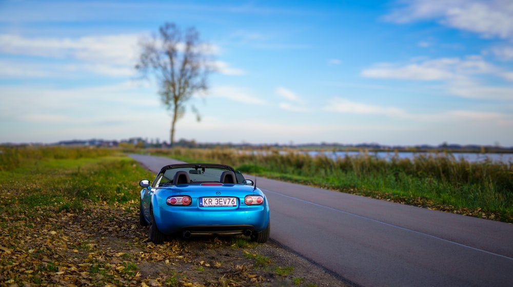 um pequeno carro azul estacionado na beira de uma estrada