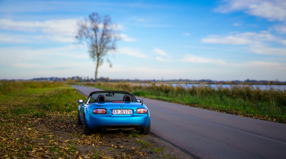 a small blue car parked on the side of a road